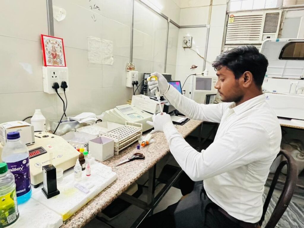 Lab technician performing blood test with various machines around him